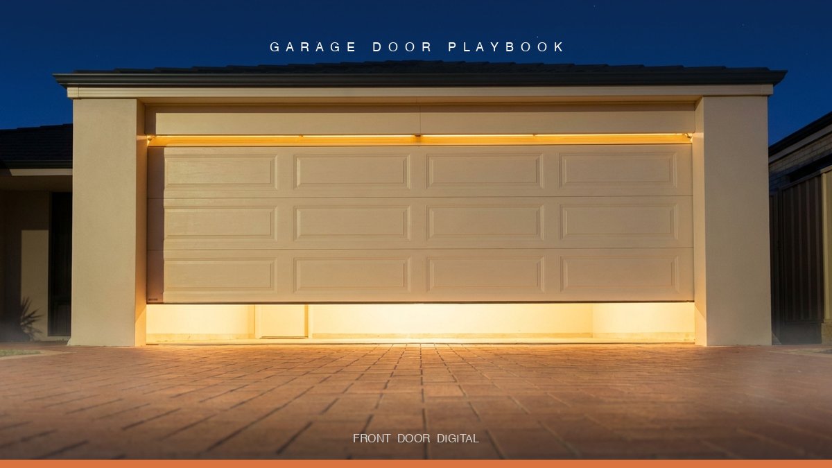 Modern American suburban two-car garage door at dusk with warm interior light spilling onto a brick driveway