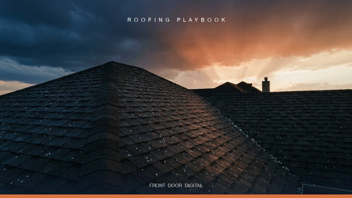Aerial view of a residential asphalt-shingle roof after a hailstorm with a navy-to-terracotta sunset sky